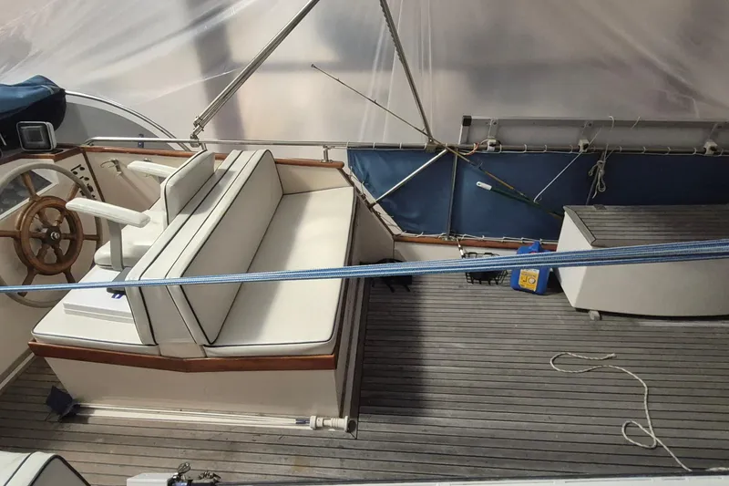 Slide: The Image of 1985 Grand Banks 42 Classic yacht interior with wooden helm, cushioned seating, and nautical decor. - 79