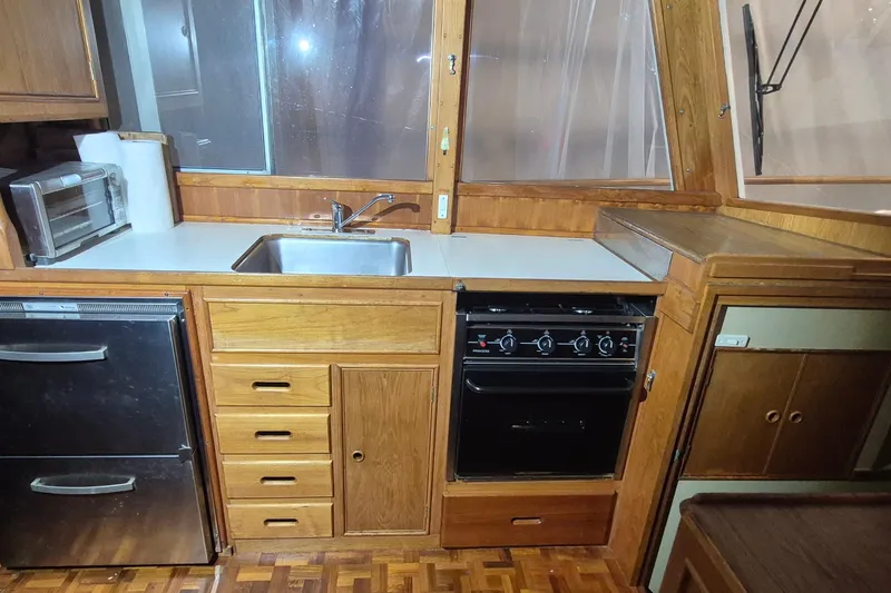 Slide: The Image of 1985 Grand Banks 42 Classic yacht kitchen with wood cabinetry, sink, stove, and appliances. - 8