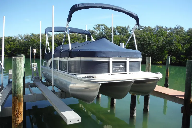 Slide: The Image of 2019 Bennington SX 22 SSRX pontoon boat docked on a lift in a serene waterway. - 33