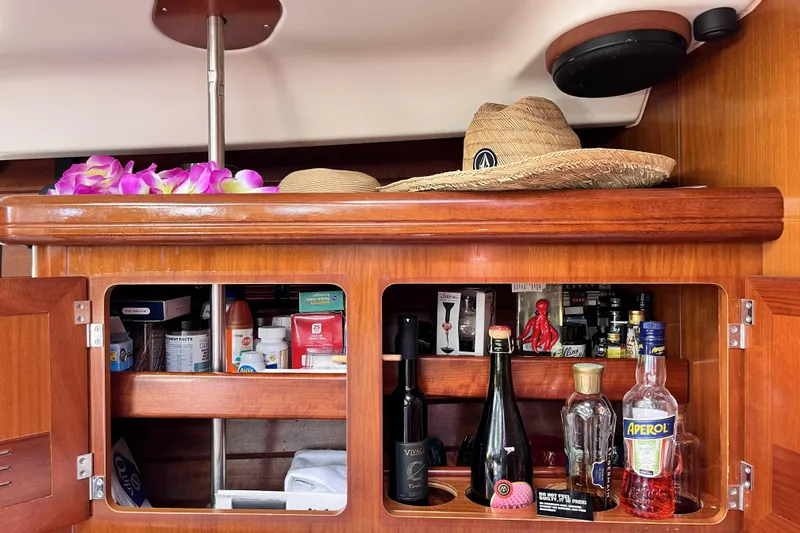 Slide: The Image of Wooden cabinet on 2001 Beneteau 473 yacht with hats, drinks, and essentials. - 13
