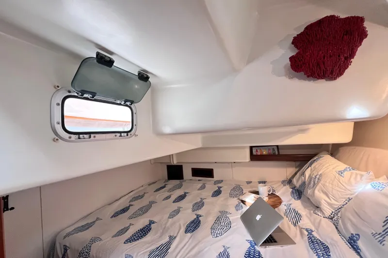 Slide: The Image of Cozy cabin interior of 2001 Beneteau 473 sailboat with open porthole and laptop on bed. - 18