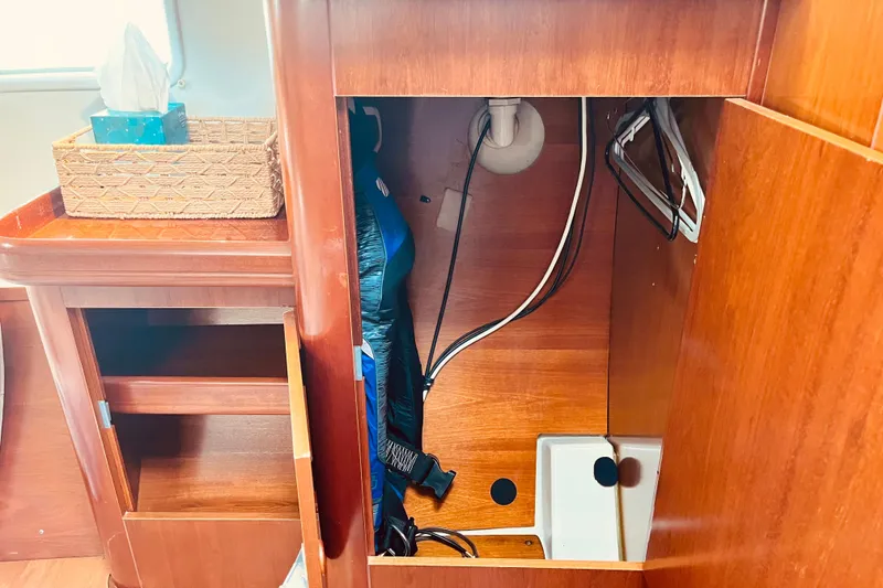 Slide: The Image of Interior view of a 2001 Beneteau 473 sailboat, showcasing wooden cabinetry and storage space. - 21