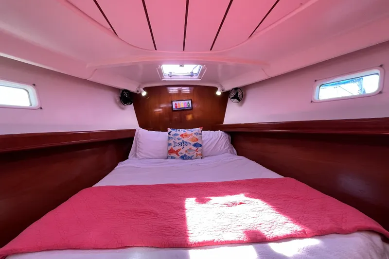 Slide: The Image of Cozy cabin interior of 2001 Beneteau 473 sailboat with pink bedding and wooden accents. - 25