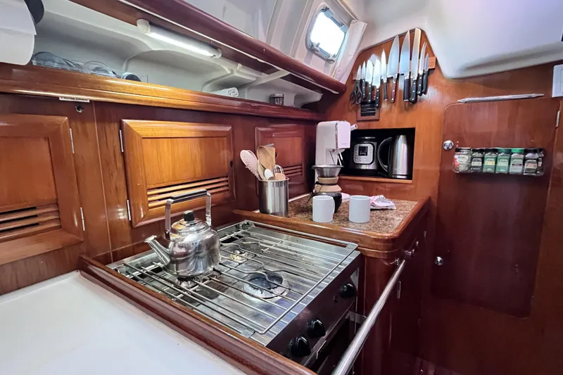 Slide: The Image of Cozy kitchen in 2001 Beneteau 473 yacht with stove, kettle, and wooden cabinetry. - 31