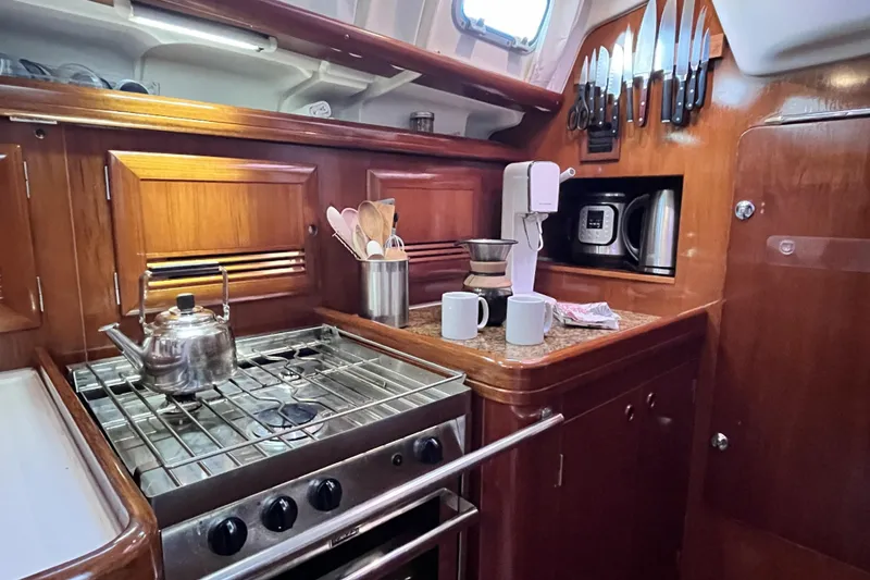 Slide: The Image of 2001 Beneteau 473 yacht kitchen with stove, kettle, and wooden cabinetry. - 33