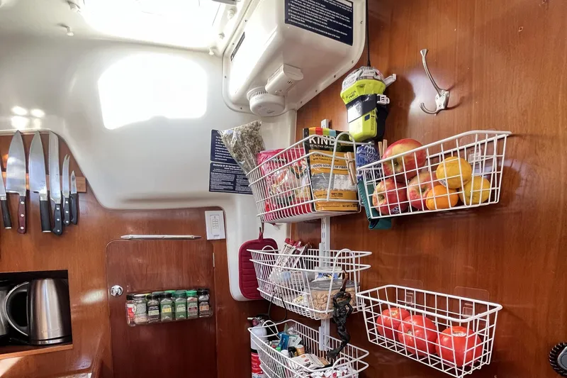 Slide: The Image of Interior of a 2001 Beneteau 473 sailboat galley with organized storage baskets and knives. - 37