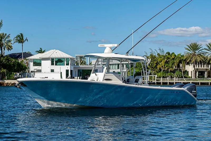The Image of 2021 Cobia 320 Center Console boat on water, with modern waterfront homes in background. - 0