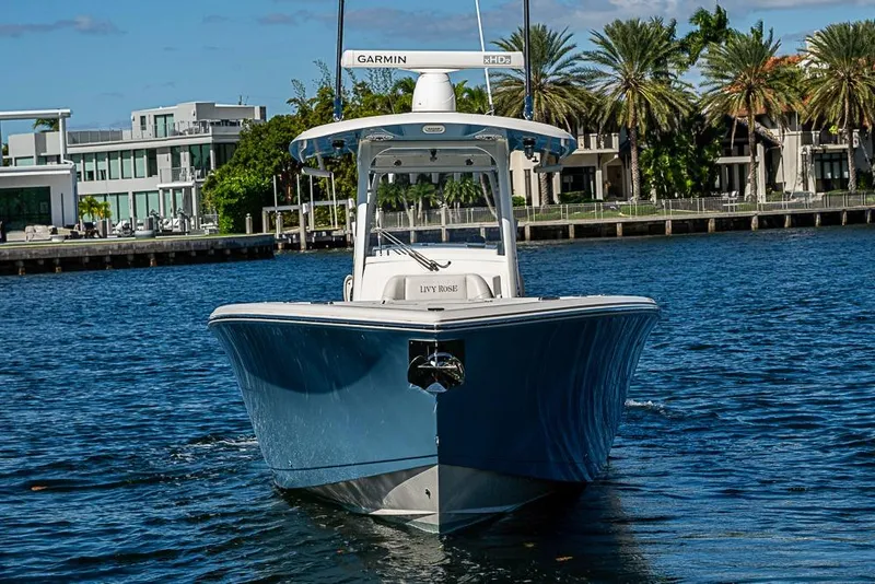 Slide: The Image of 2021 Cobia 320 Center Console boat on water, with modern waterfront homes in background. - 23