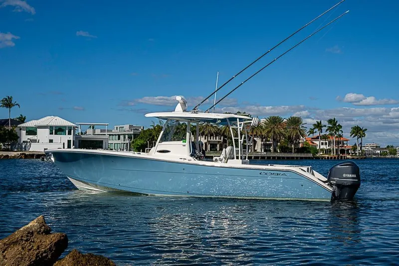 Slide: The Image of 2021 Cobia 320 Center Console boat on water, with coastal homes in the background. - 25