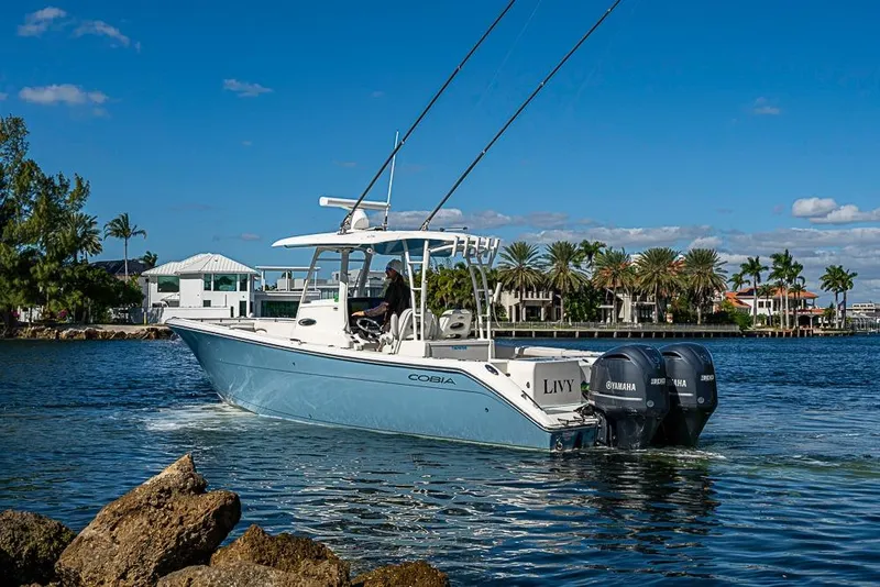 Slide: The Image of 2021 Cobia 320 Center Console boat cruising on a sunny day near waterfront homes. - 26