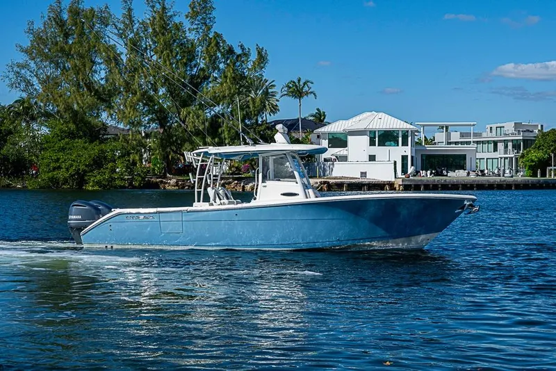 Slide: The Image of 2021 Cobia 320 Center Console boat cruising on a sunny day near waterfront homes. - 32
