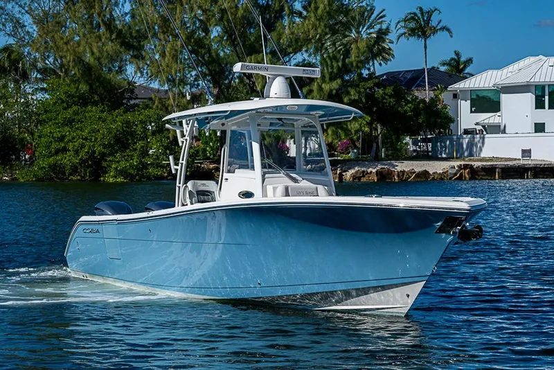 Slide: The Image of 2021 Cobia 320 Center Console boat cruising on a sunny day near waterfront homes. - 33