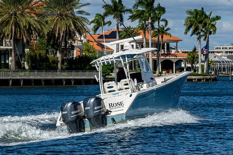 Slide: The Image of 2021 Cobia 320 Center Console boat cruising on a scenic waterway with palm trees. - 38