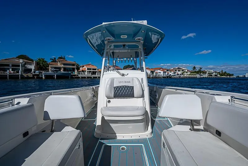 Slide: The Image of 2021 Cobia 320 Center Console boat on water with luxury seating and waterfront homes. - 4