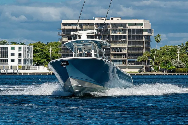 Slide: The Image of 2021 Cobia 320 Center Console boat cruising on water near modern buildings. - 42