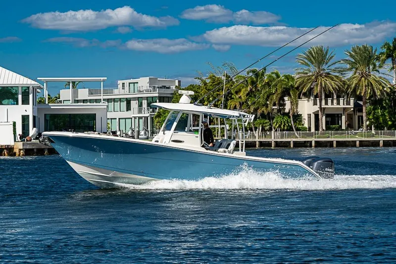 Slide: The Image of 2021 Cobia 320 Center Console boat cruising on a sunny day near waterfront homes. - 44