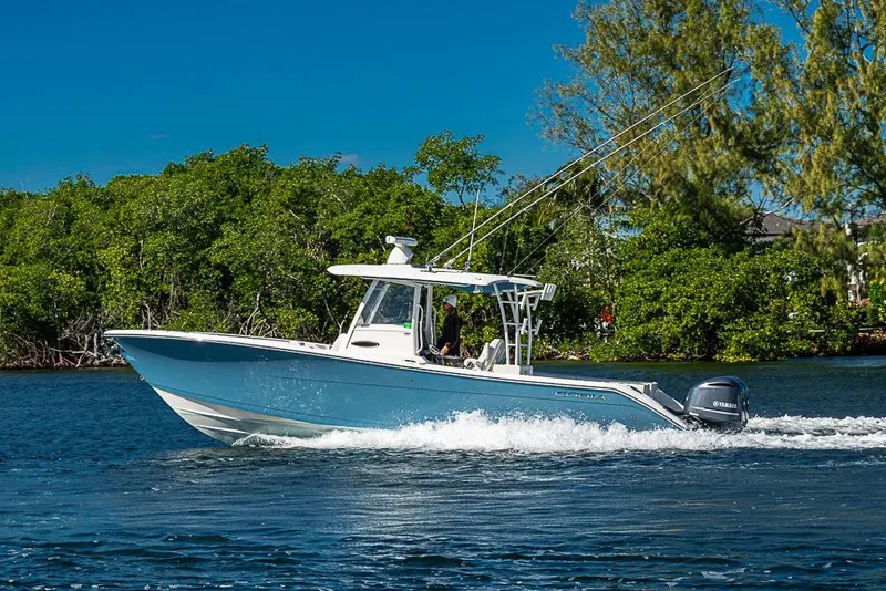 Slide: The Image of 2021 Cobia 320 Center Console boat cruising on a sunny day near lush greenery. - 45