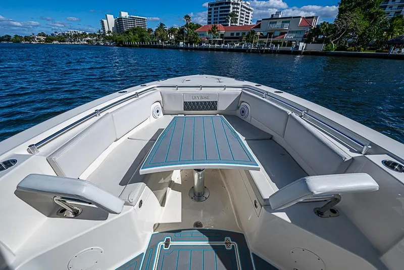Slide: The Image of 2021 Cobia 320 Center Console boat interior with seating and table on calm water. - 5