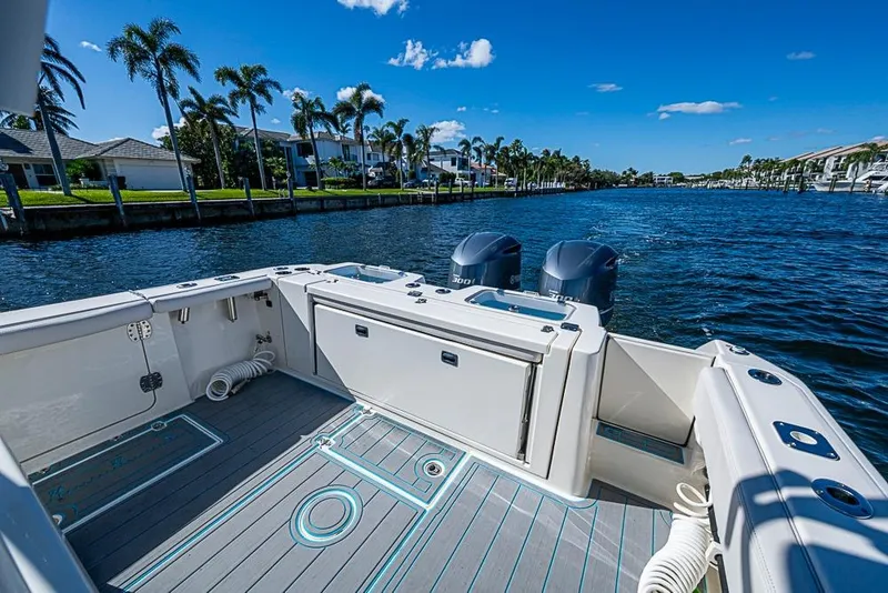 Slide: The Image of 2021 Cobia 320 Center Console boat on a sunny waterfront with palm trees. - 7