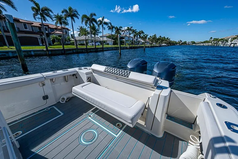Slide: The Image of 2021 Cobia 320 Center Console boat on a sunny waterfront with palm trees. - 8
