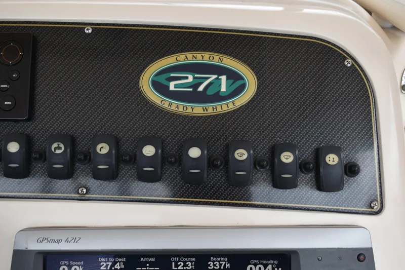 Slide: The Image of 2012 Grady-White Canyon 271 boat interior with helm and seating, docked by the water. - 17