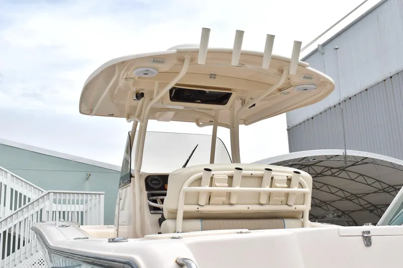 Slide: The Image of 2012 Grady-White Canyon 271 boat with T-top and rod holders, docked near a building. - 5