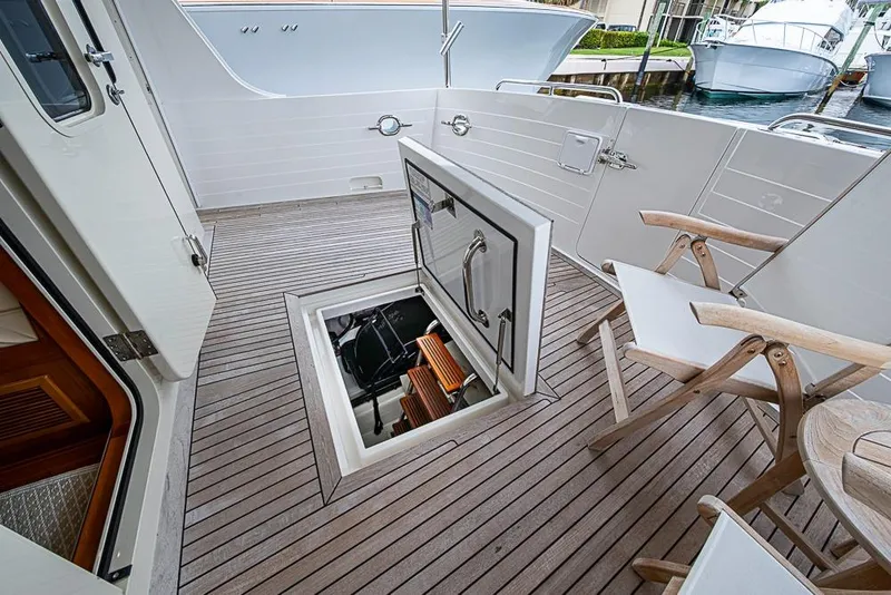 Slide: The Image of 2016 Kadey-Krogen 52 yacht deck with open hatch and wooden chairs. - 49