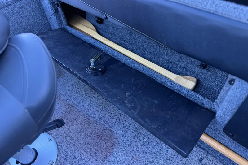 Slide: The Image of 2023 Tracker Targa V-19 WT boat interior with storage compartment and paddle. - 20