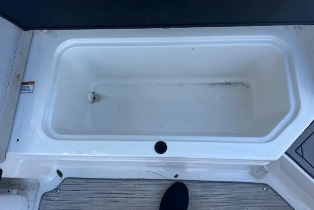 Slide: The Image of 2022 Sea Ray SPX 210 storage compartment, white interior, open lid view. - 24