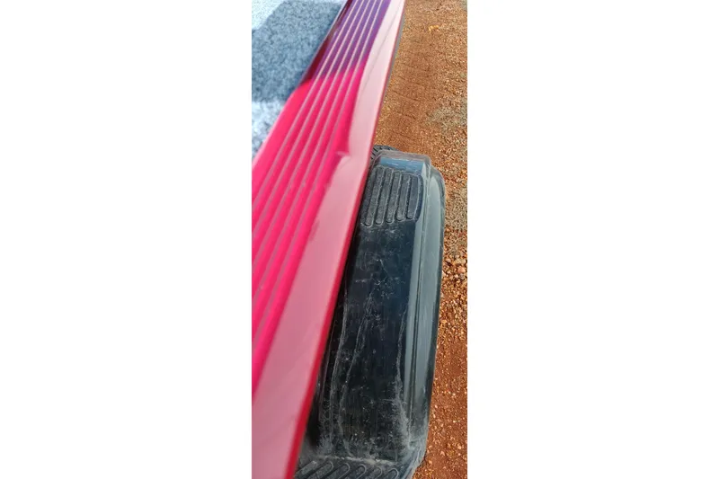 Slide: The Image of 2026 Tracker Bass Tracker Classic XL boat detail, red and black components on dirt background. - 19
