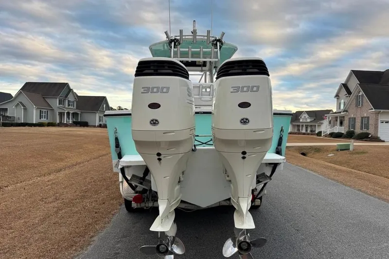 Slide: The Image of 2003 Regulator 26 Forward Seating boat with twin 300 horsepower engines, parked in a suburban neighborhood. - 1