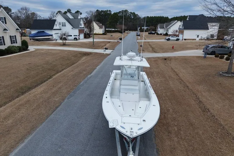 Slide: The Image of 2003 Regulator 26 Forward Seating boat on residential street, surrounded by houses. - 11