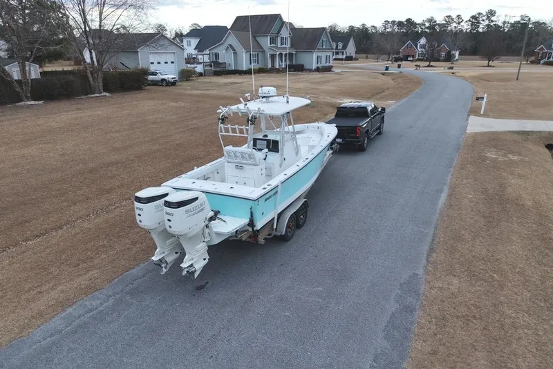 Slide: The Image of 2003 Regulator 26 Forward Seating boat on trailer, towed by a truck in suburban neighborhood. - 15