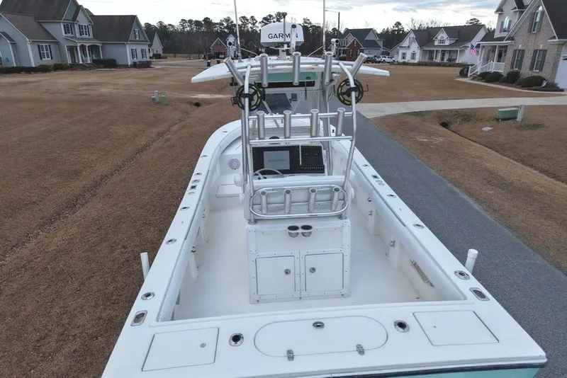 Slide: The Image of 2003 Regulator 26 Forward Seating boat on a residential street, showcasing its deck and console. - 16