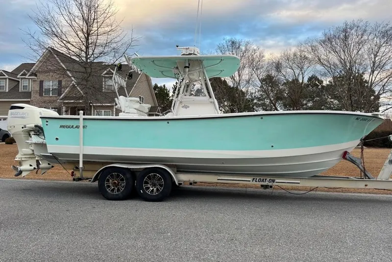 Slide: The Image of 2003 Regulator 26 Forward Seating boat on trailer, parked in suburban neighborhood. - 5