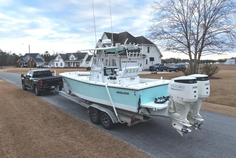 Slide: The Image of 2003 Regulator 26 Forward Seating boat on trailer, towed by a black truck in suburban neighborhood. - 7