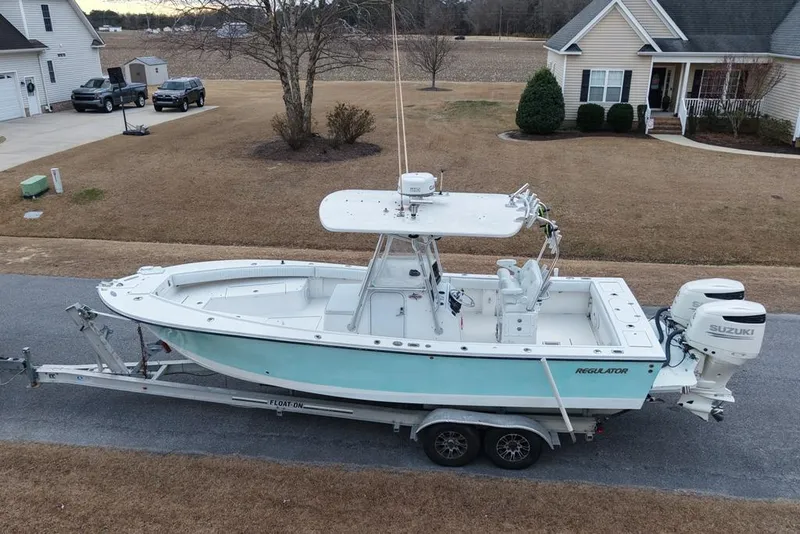 Slide: The Image of 2003 Regulator 26 Forward Seating boat on trailer, parked in suburban neighborhood. - 8