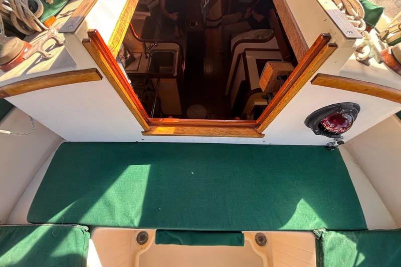 Slide: The Image of Interior view of 1983 Bristol Channel Cutter 28 sailboat, featuring wooden trim and green upholstery. - 12