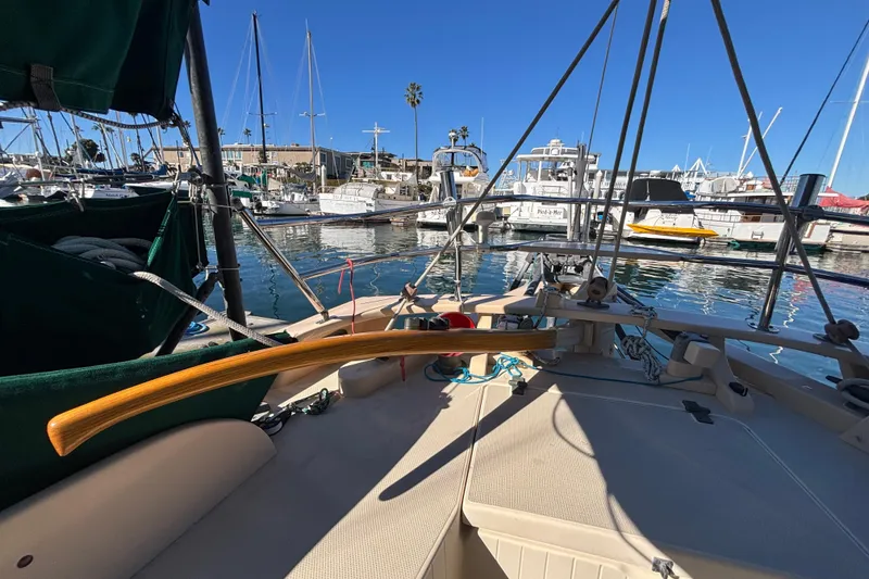 Slide: The Image of 1983 Bristol Channel Cutter 28 sailboat docked in a marina, featuring a wooden tiller. - 20