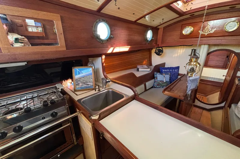 Slide: The Image of Interior of 1983 Bristol Channel Cutter 28 sailboat with cozy wooden design and kitchen area. - 36