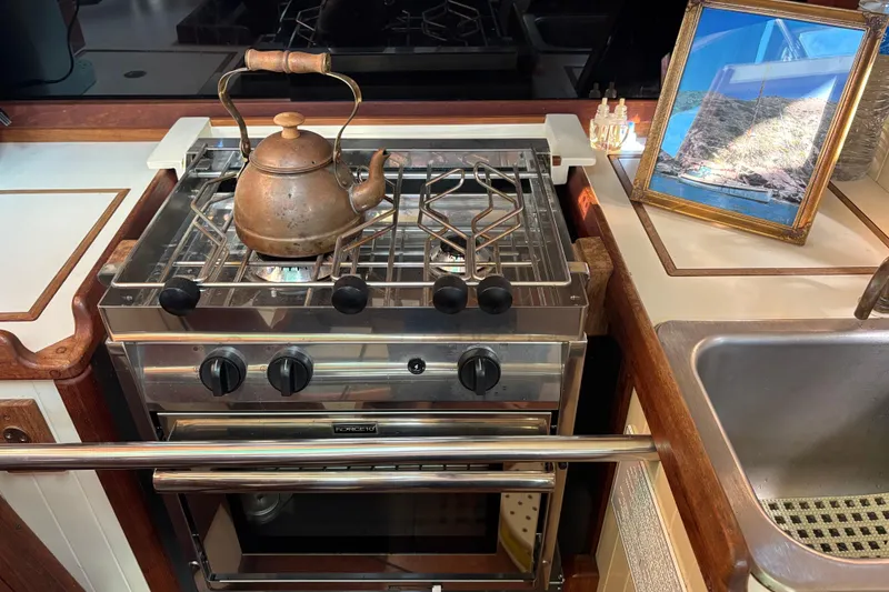 Slide: The Image of Galley kitchen in 1983 Bristol Channel Cutter 28 with stove, kettle, and framed photo. - 39