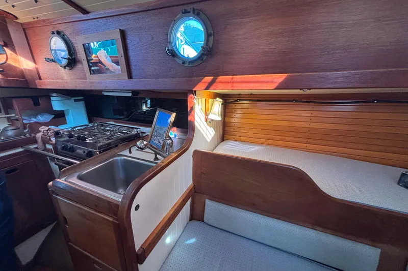 Slide: The Image of 1983 Bristol Channel Cutter 28 interior with wooden cabinetry, sink, stove, and cozy seating area. - 42