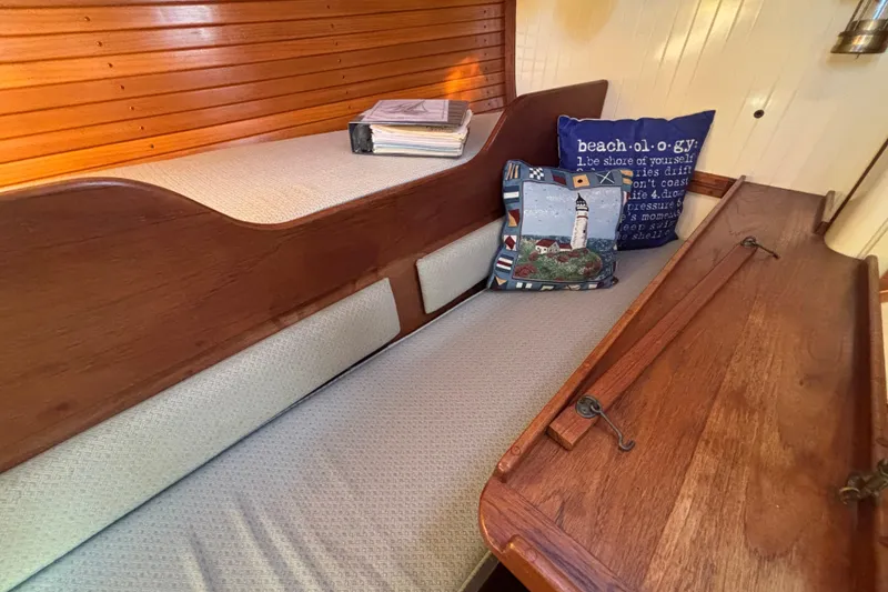 Slide: The Image of Cozy interior of 1983 Bristol Channel Cutter 28 with nautical-themed cushions and wooden accents. - 49