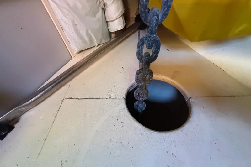 Slide: The Image of Anchor chain descending into a deck opening on a 1983 Bristol Channel Cutter 28 sailboat. - 58