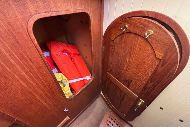 Slide: The Image of Wooden cabin interior of 1983 Bristol Channel Cutter 28, featuring life jackets in storage. - 65