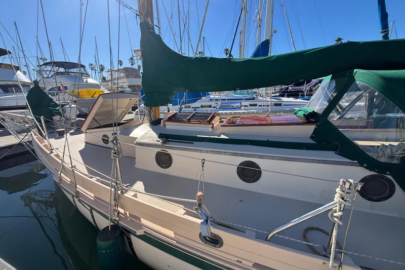 Slide: The Image of 1983 Bristol Channel Cutter 28 sailboat docked in marina, featuring green covers and classic design. - 7