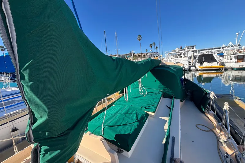 Slide: The Image of 1983 Bristol Channel Cutter 28 sailboat with green covers docked in a marina. - 78