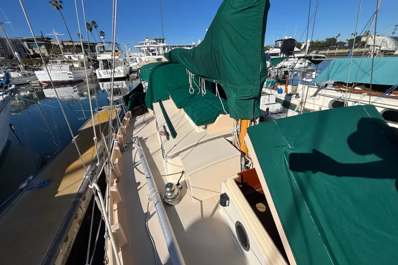 Slide: The Image of 1983 Bristol Channel Cutter 28 sailboat docked, featuring green covers and a sunny marina setting. - 79