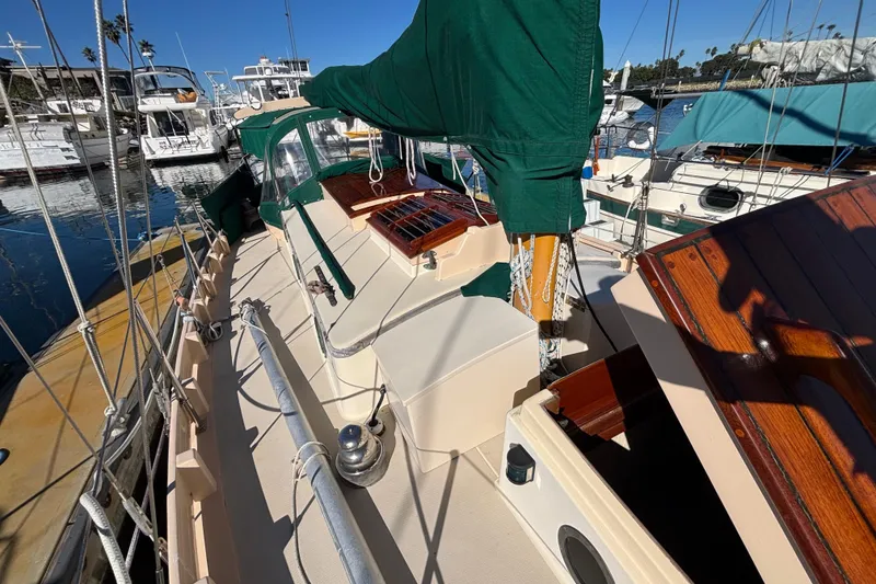 Slide: The Image of 1983 Bristol Channel Cutter 28 sailboat with green covers docked in a marina. - 8