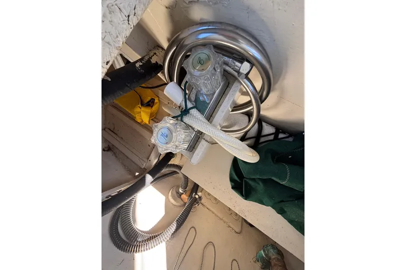 Slide: The Image of Plumbing system inside 1983 Bristol Channel Cutter 28 sailboat, featuring hoses and valves. - 83